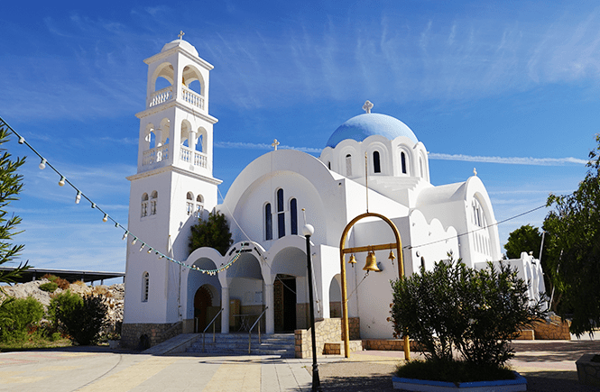 Photo of a white church with a blue dome roof in Aegina, Greece.